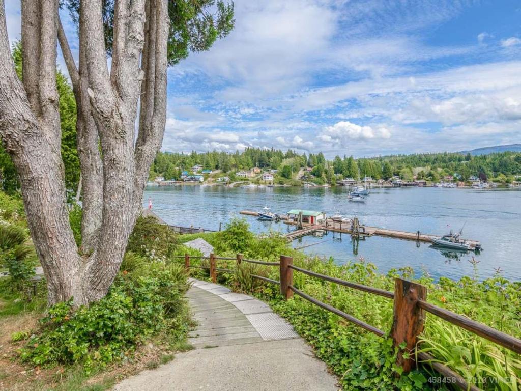 una valla de madera junto a un río con muelle en Woods End Landing en Bamfield