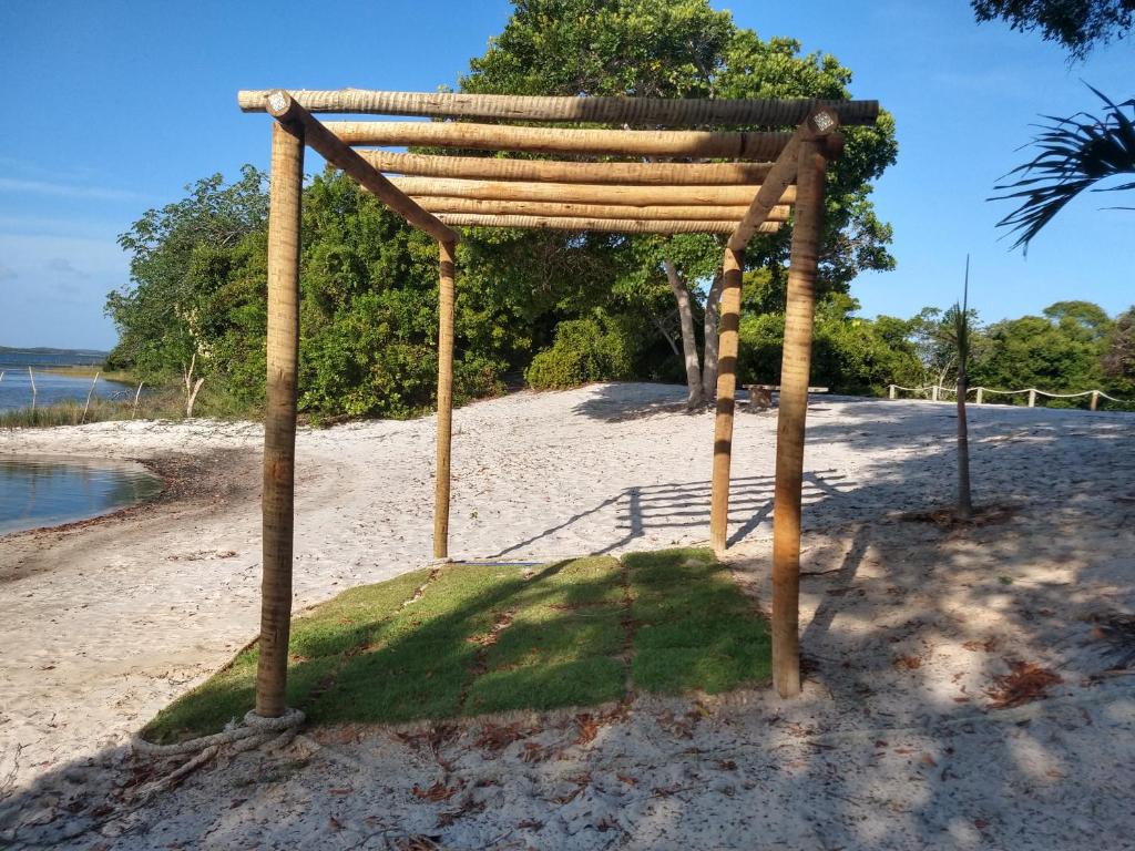 a wooden pergola on a beach near the water at Casa da Lagoa Azul - Tambaquis - Abaís in Estância