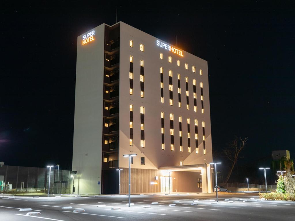 能美市にあるスーパーホテル石川・能美根上スマートインターの夜間の看板が貼られた高層ビル