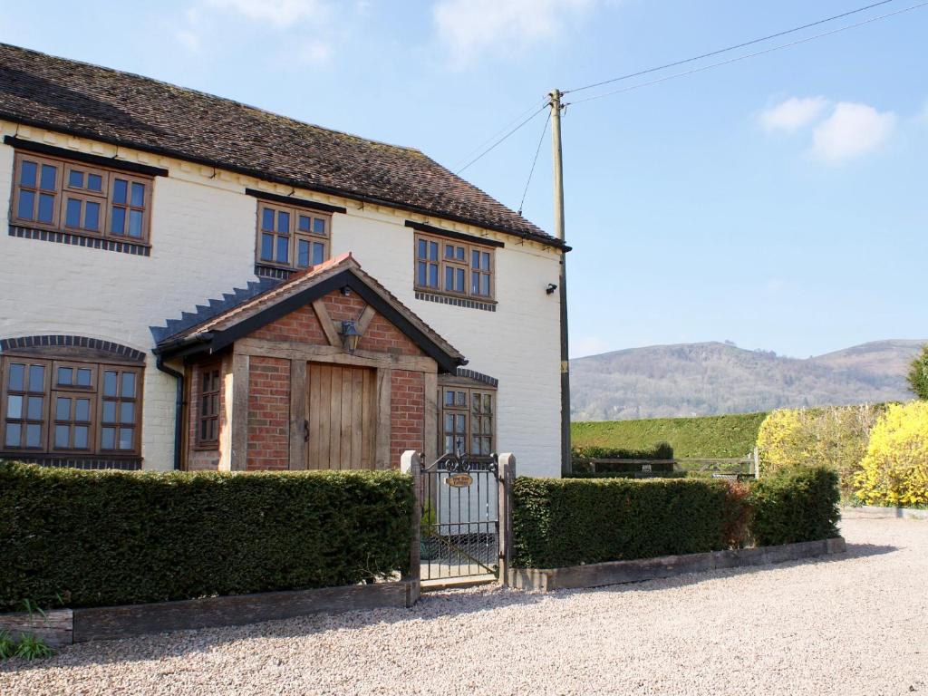 a white house with a gate in front of it at Yew Tree Cottage in Great Malvern