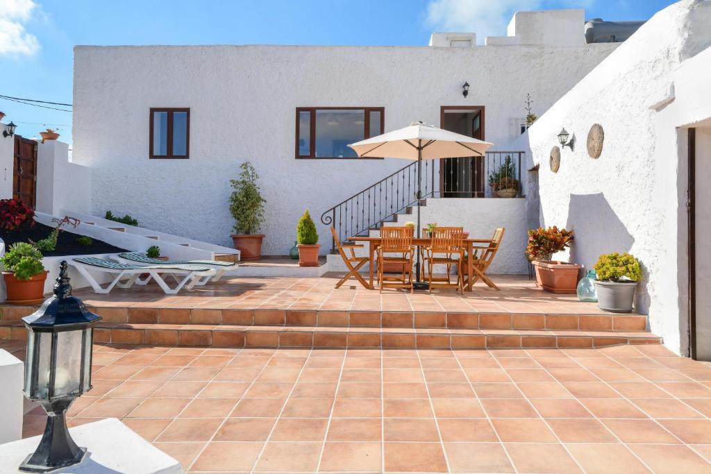 a patio with a table and chairs and an umbrella at Casa Maria Dolores in Haría