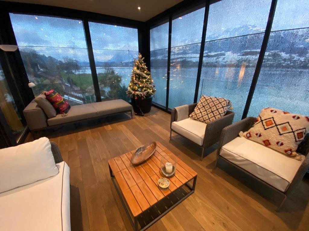 a living room with a christmas tree in a room with windows at Luxury loft on top of Villa Wilen with tremendous views by the lake in Sarnen