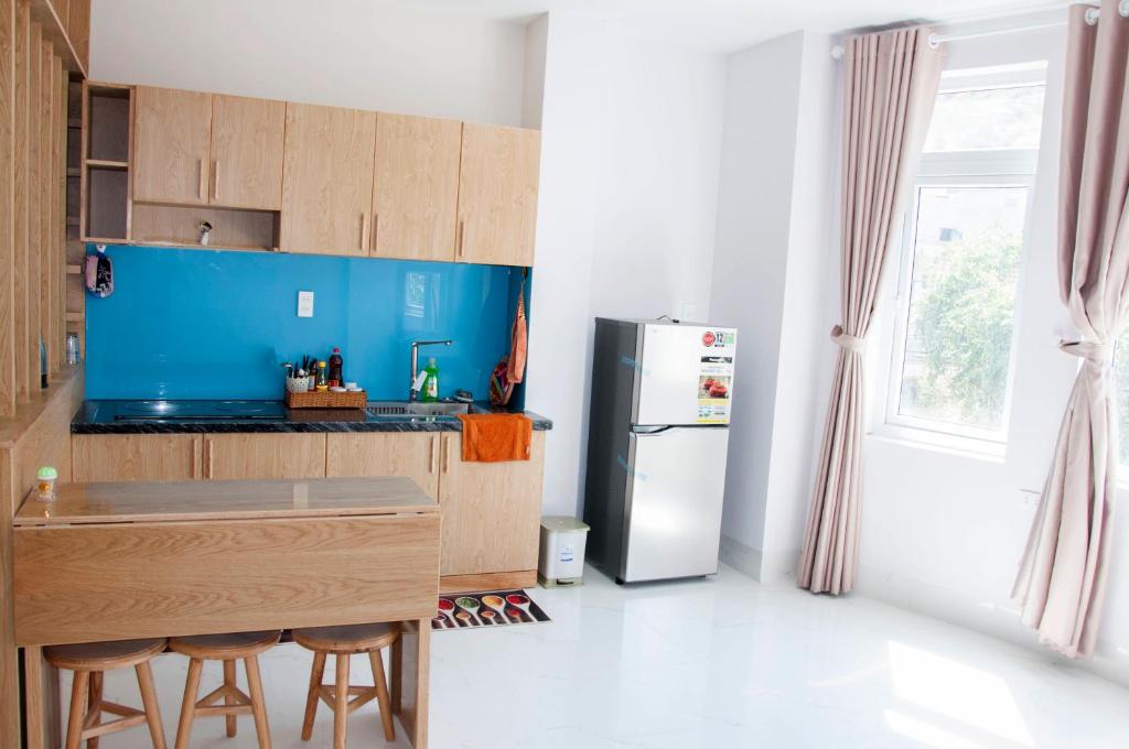 a kitchen with a refrigerator and a counter with stools at COCA HOTEL & APARTMENT in Vung Tau