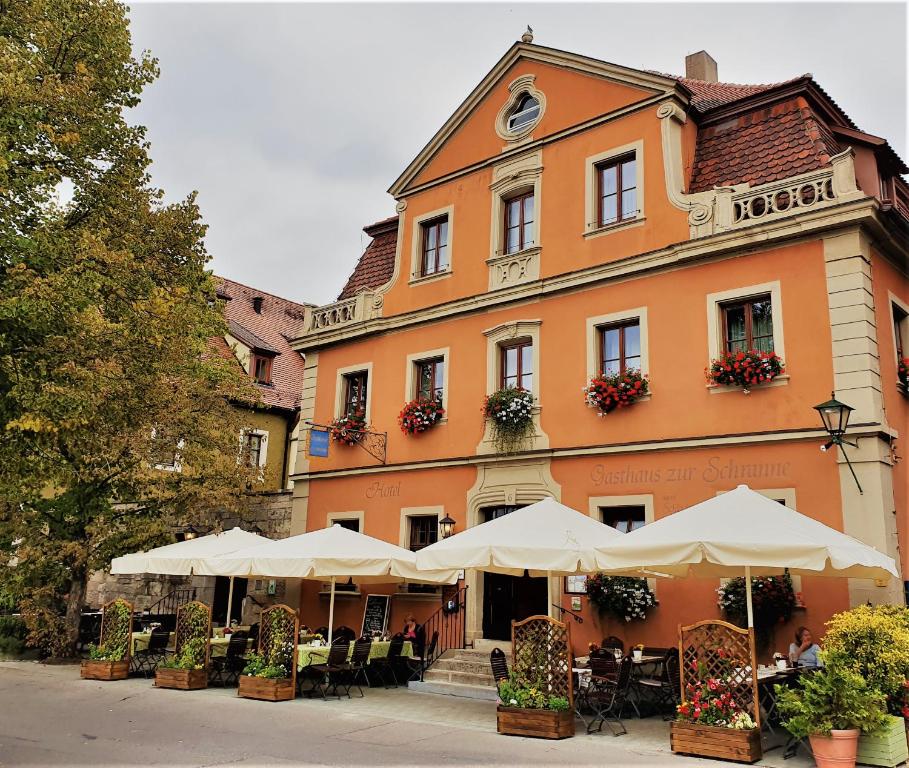un edificio con tavoli e ombrelloni di fronte ad esso di Akzent Hotel Schranne a Rothenburg ob der Tauber