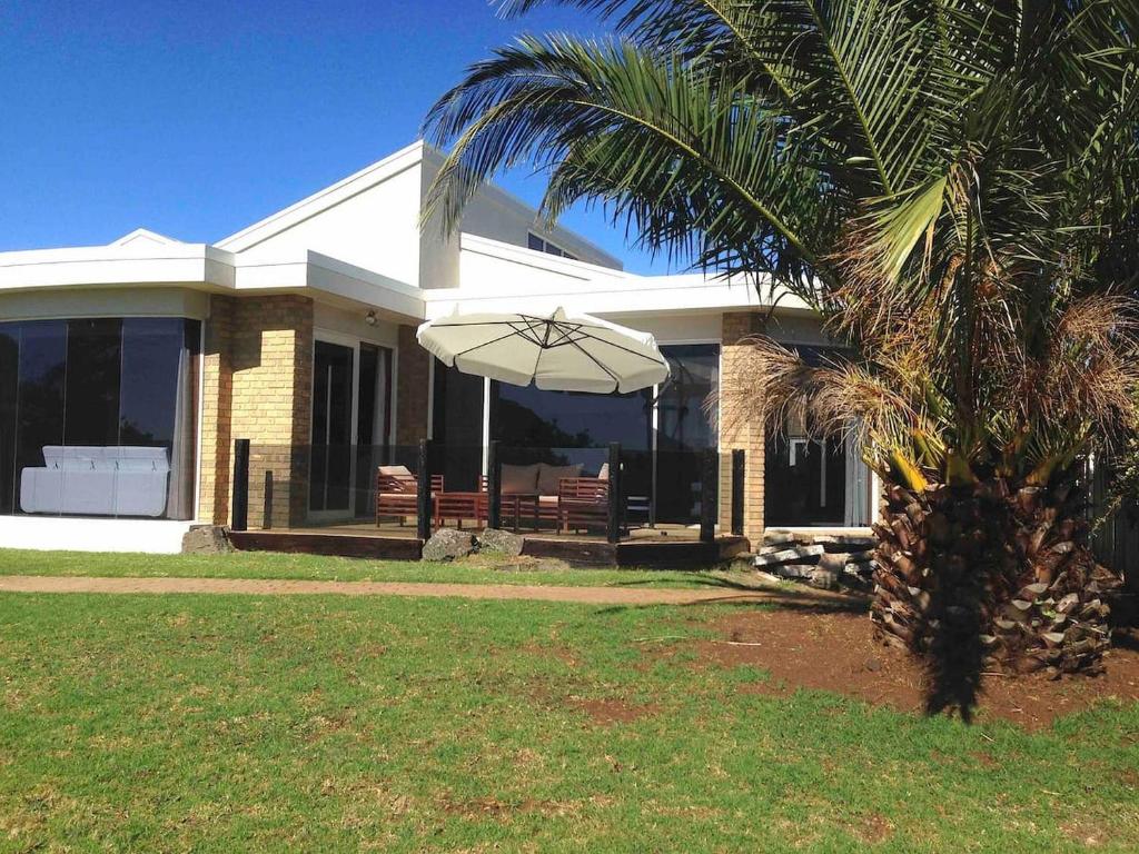 a house with a palm tree and an umbrella at Bayviews at Newhaven in Newhaven