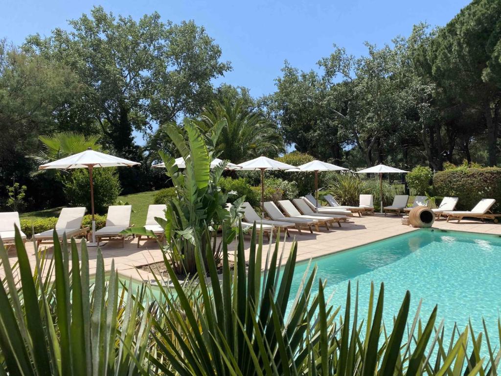 una piscina con tumbonas y sombrillas en GOLF HOTEL en La Grande-Motte