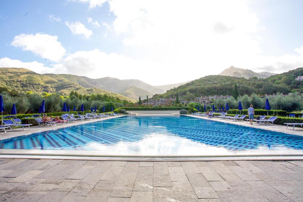 uma piscina com cadeiras e montanhas ao fundo em Sant'Anna Vicolo Aranci 5 em Portoferraio