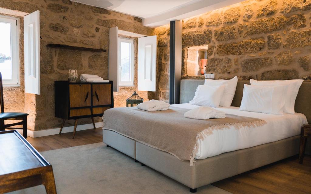 a bedroom with a large bed with a stone wall at Casa da Ana Boutique Guest House in Barcelos