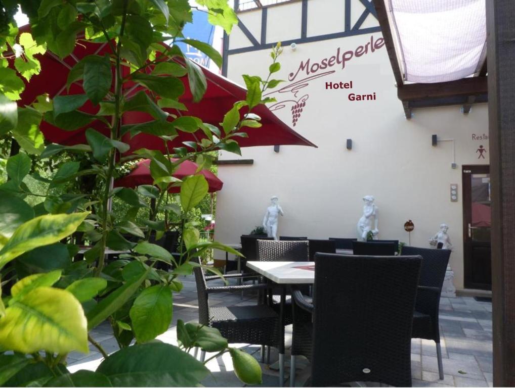 ein Restaurant mit einem Tisch, Stühlen und Pflanzen in der Unterkunft Moselperle Hotel Garni in Wolf