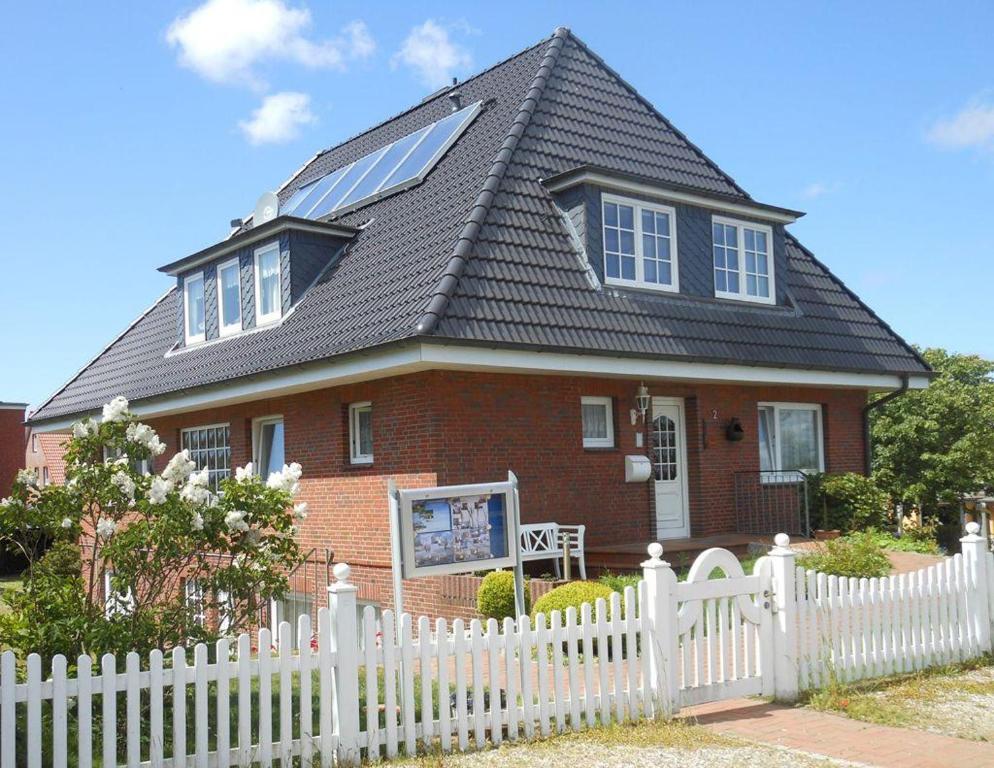 ein Haus mit einem weißen Zaun davor in der Unterkunft Ferienhaus "Heißer Sand", Whg 7 in Wittdün