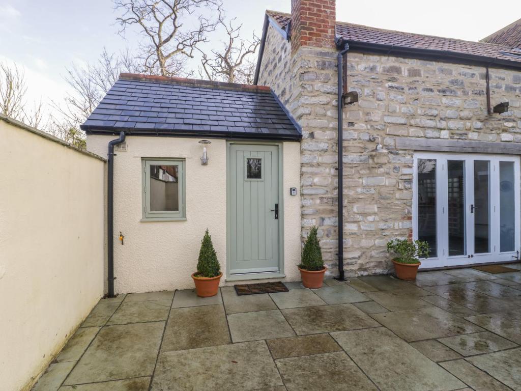 uma casa de pedra com uma porta verde e um pátio em Magnolia Barn em Highbridge