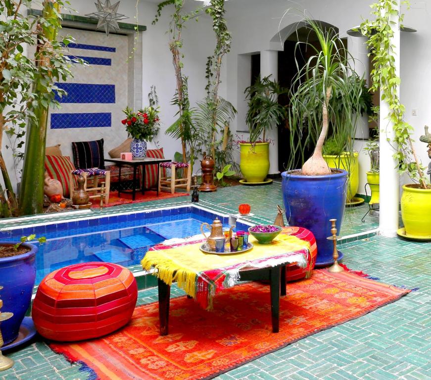 een patio met een tafel en een zwembad met planten bij Riad Bobby Marrakech in Marrakesh