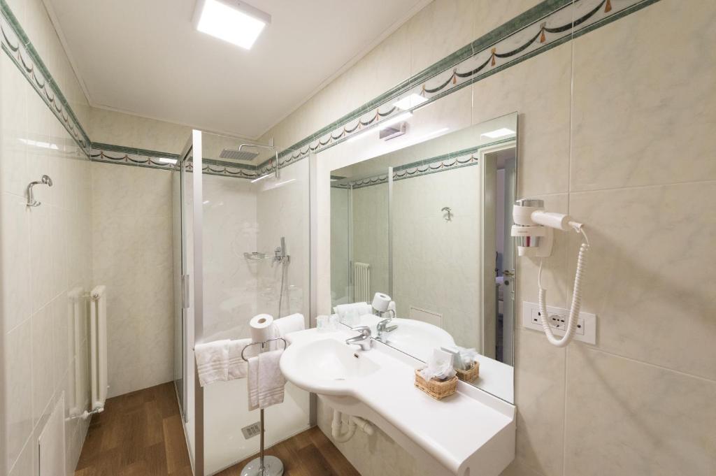 a white bathroom with a sink and a shower at Grand Hotel Liberty in Riva del Garda