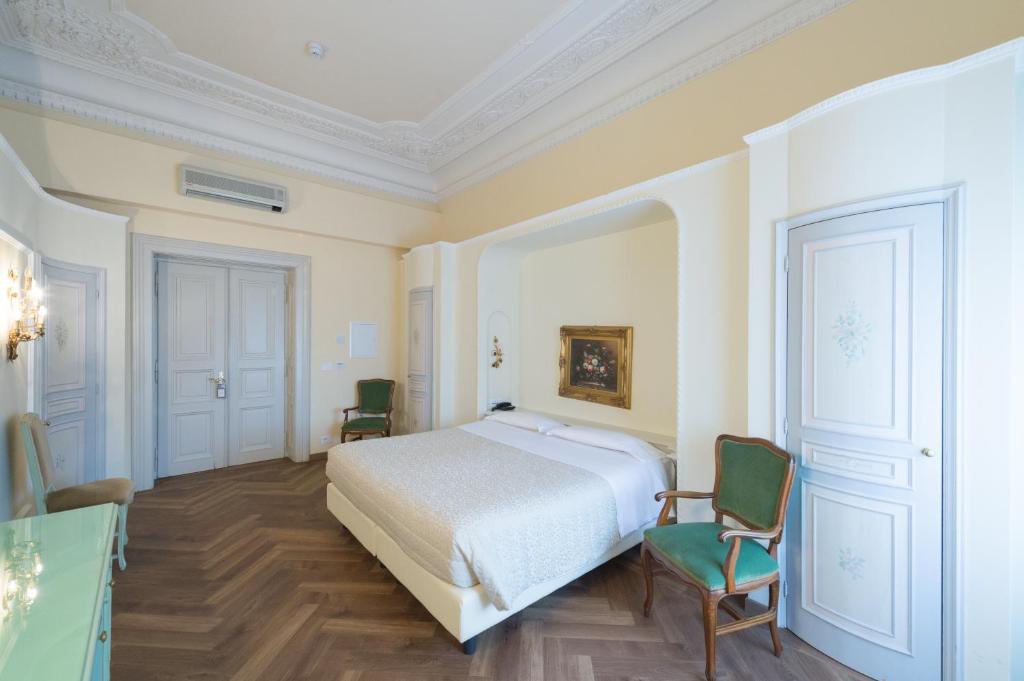 a bedroom with a white bed and two chairs at Grand Hotel Liberty in Riva del Garda