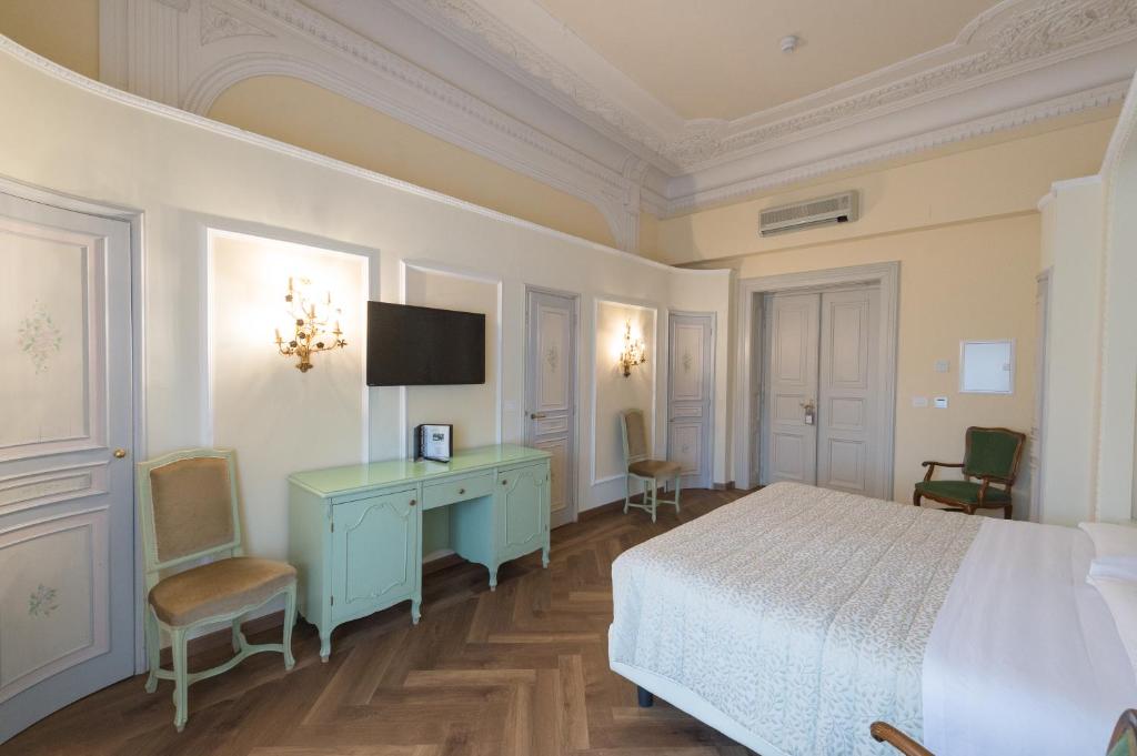 a bedroom with a bed and a desk and a tv at Grand Hotel Liberty in Riva del Garda