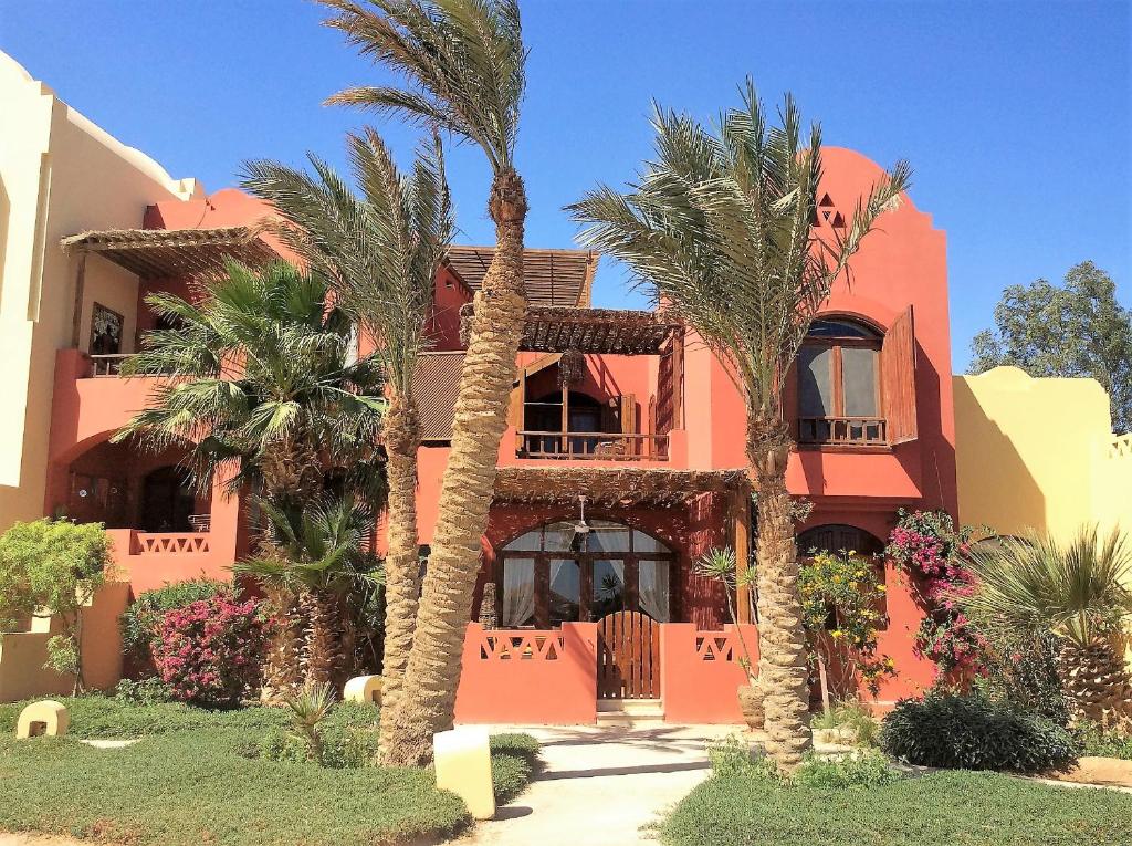 un edificio rosa con palmeras delante en Villa Melody - Holiday home in El Gouna, en Hurghada