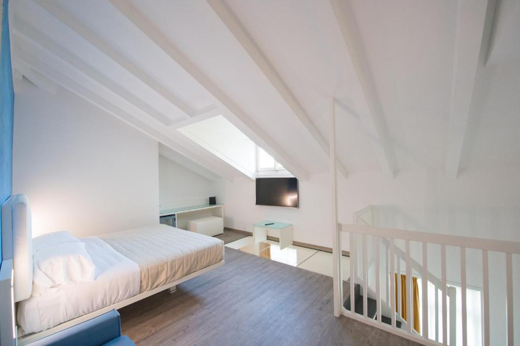 a white bedroom with a bed and a staircase at Grand Hotel Liberty in Riva del Garda