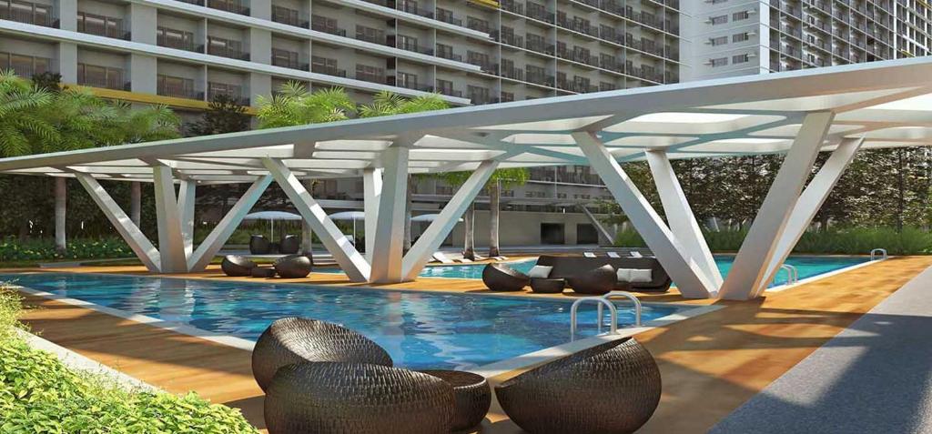 una gran piscina con sillas y un gran edificio en Fame Residences T1 Family Suite 1507 en Manila