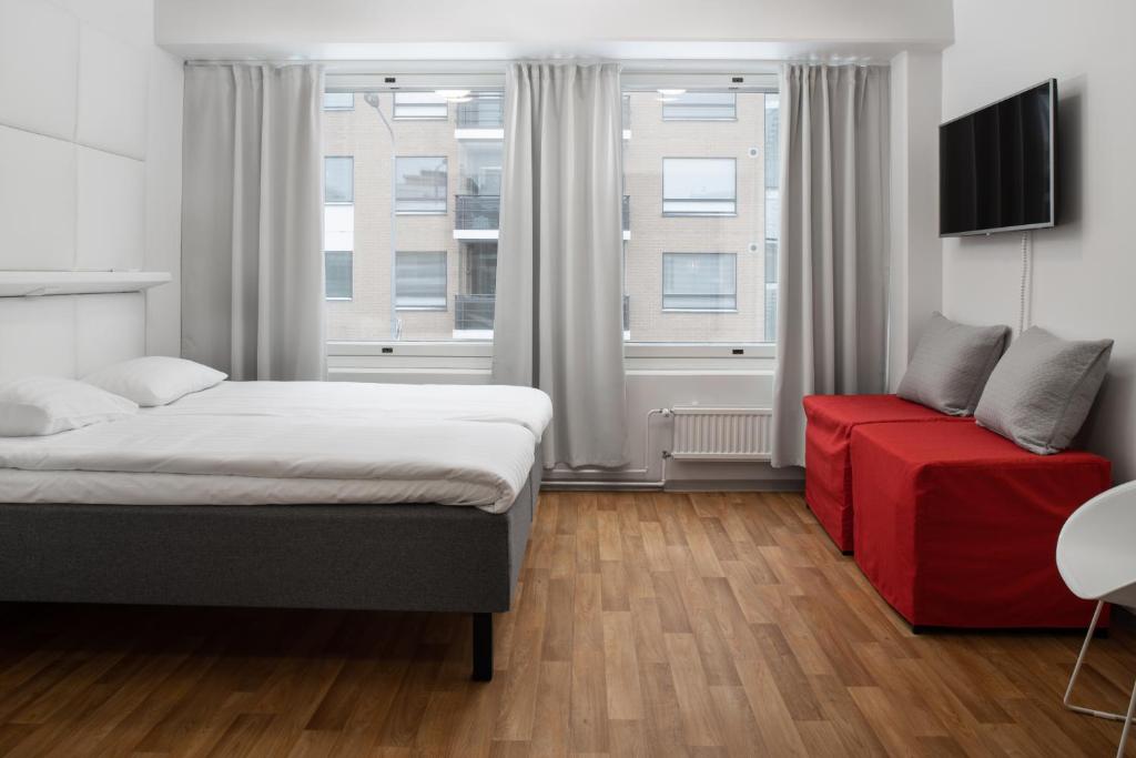 a bedroom with a bed and a red couch at Omena Hotel Pori in Pori