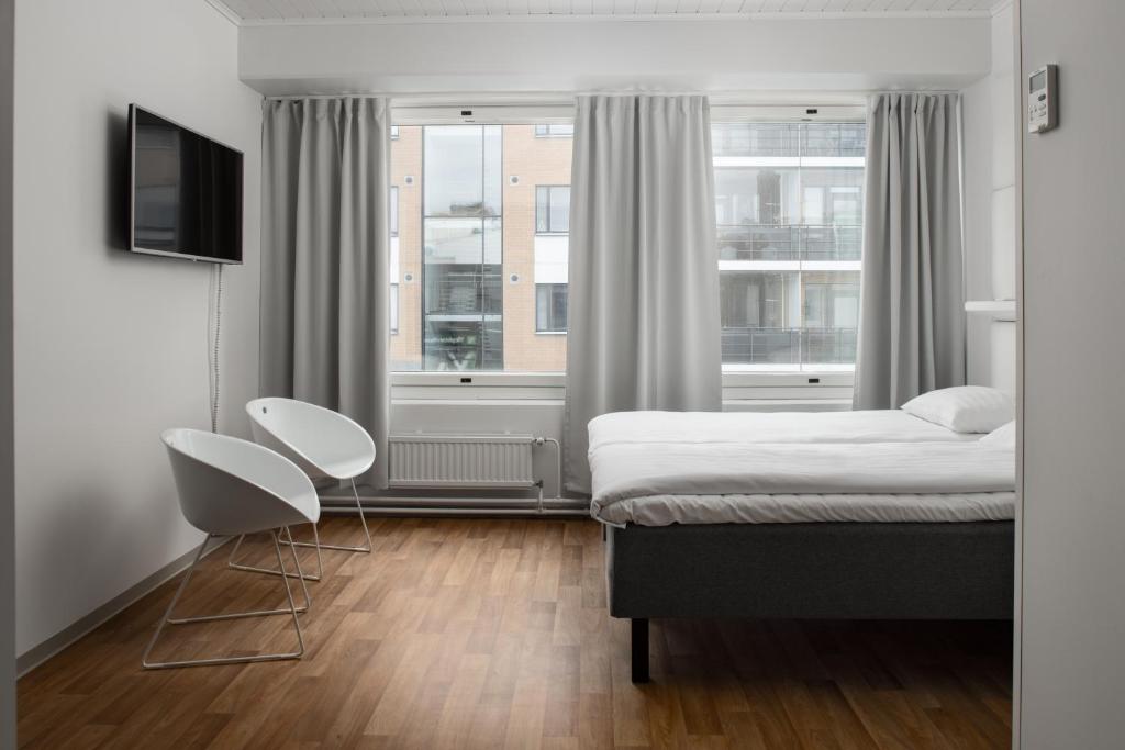 1 dormitorio con 1 cama, 2 sillas y ventana en Omena Hotel Pori, en Pori