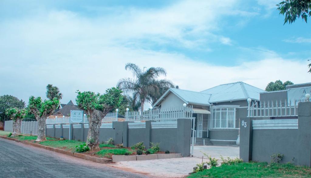 a fence in front of a house with trees at KK GUEST HOUSE in Brakpan