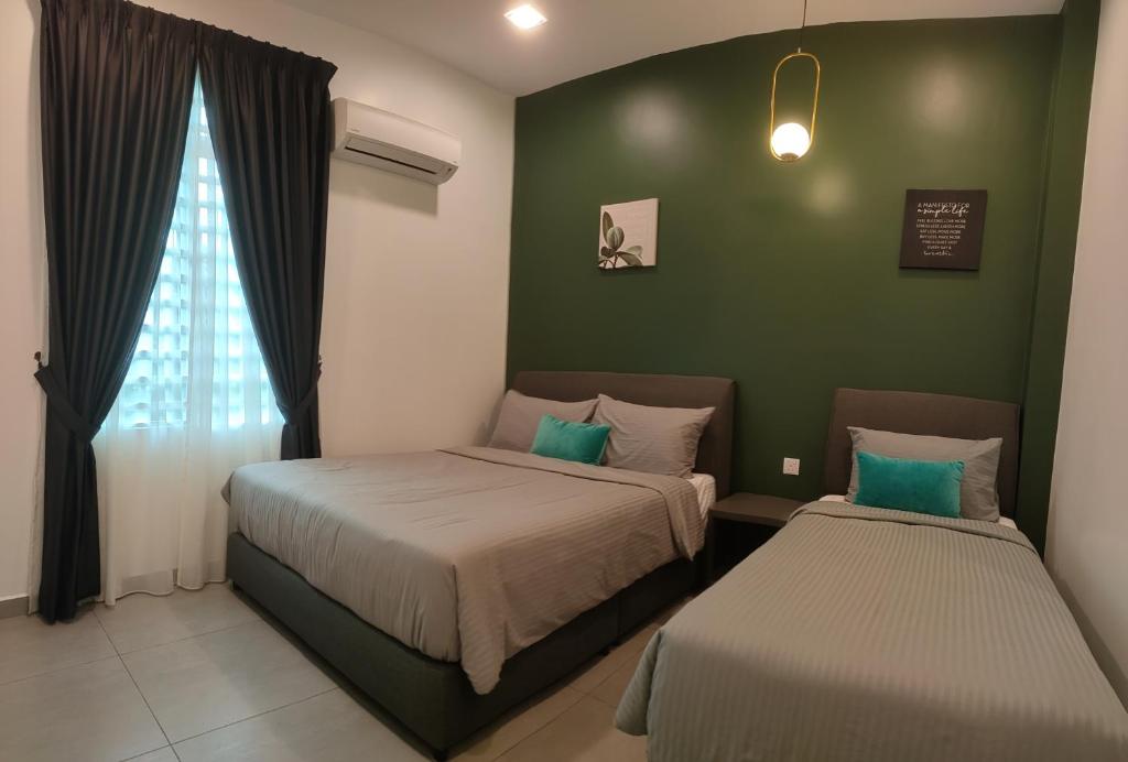 um quarto com 2 camas e uma parede verde em Just Austin Guesthouse em Ipoh