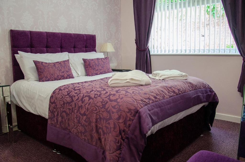 Un dormitorio con una cama grande con sábanas moradas y una ventana en The Lemonfield Hotel en Sunderland
