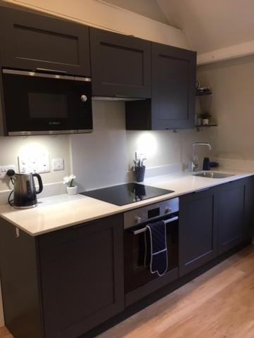 a kitchen with black cabinets and a stove top oven at Beautiful Bath Apartment in iconic Milsom Street Location in Bath