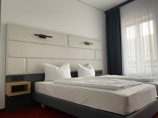 a bedroom with a large bed with a headboard and a window at Hotel Continental in Nuremberg