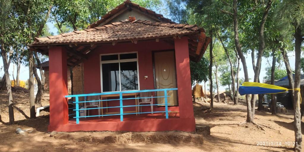 una pequeña casa roja en medio de los árboles en Niramaya beach view stay, en Gokarna