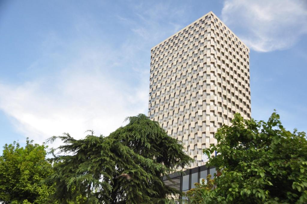 un edificio alto con árboles delante de él en Maritim Hotel Plaza Tirana en Tirana