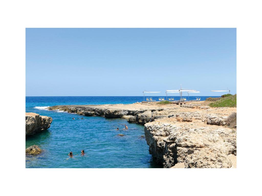 a group of people swimming in the water on a beach at Grand Hotel Masseria Santa Lucia in Ostuni