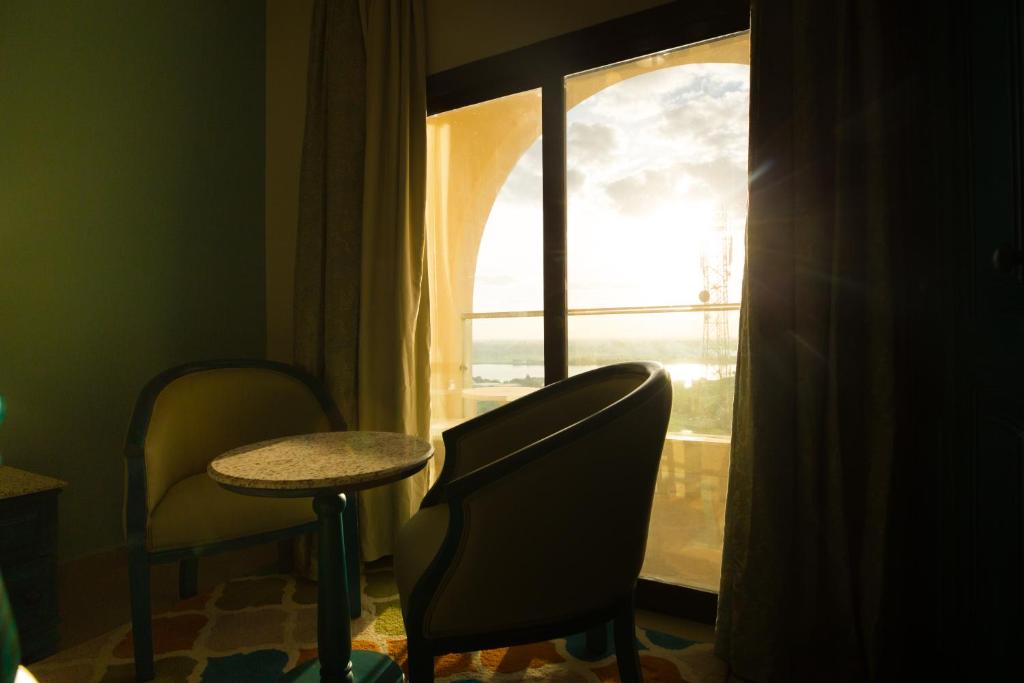 a room with a chair and a table and a window at Holy Family Hotel in Jabal aţ Ţayr