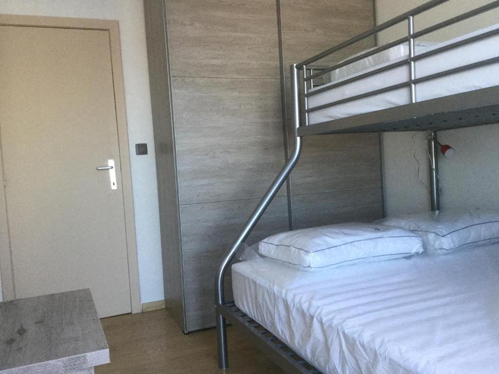 een slaapkamer met een stapelbed met een wit matras bij Panoramisch appartement tussen zee ,bos en de duinen in De Panne