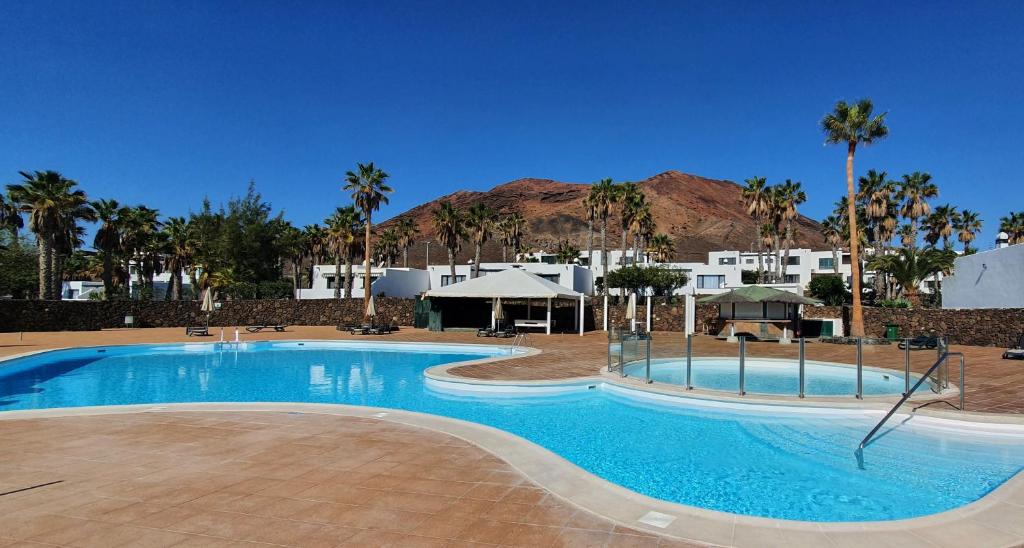 a large swimming pool with palm trees and buildings at Palmeras Garden in Playa Blanca