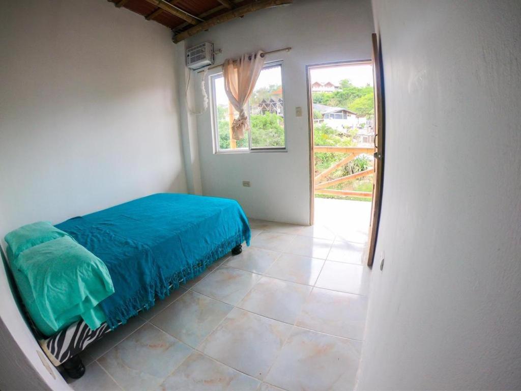 een slaapkamer met een blauw bed in een kamer met een raam bij Iguana Beach House in Montañita