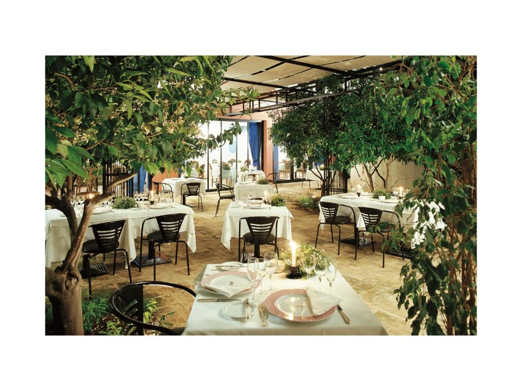 a restaurant with white tables and chairs and trees at Grand Hotel Masseria Santa Lucia in Ostuni