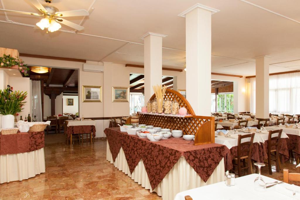 una sala da pranzo con tavoli e sedie bianchi di Hotel Arborea a Lido di Jesolo