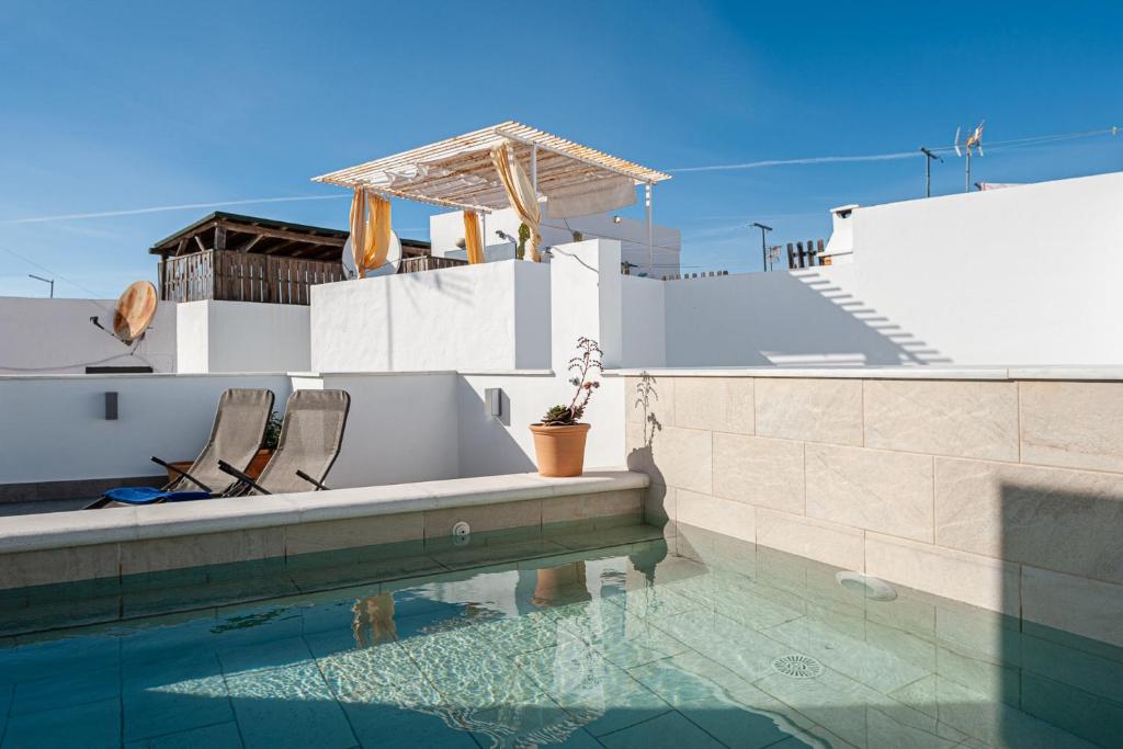 a swimming pool with two chairs and a house at Apartamentos Wamba in Conil de la Frontera