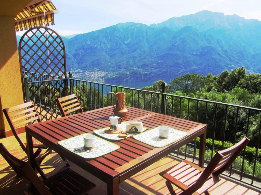 einen Holztisch auf einem Balkon mit Bergblick in der Unterkunft IL BALCONE SUL LAGO in Magreglio