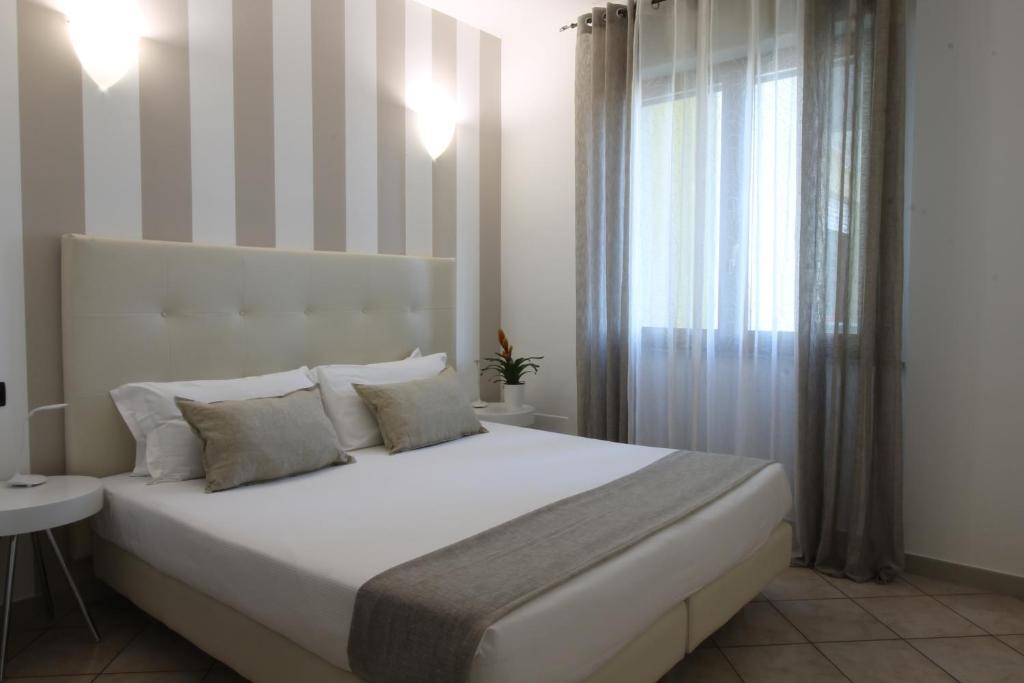 HQ Aparthotel Milano Inn - Smart Suites في شينيسيلو بالسامو: غرفة نوم بسرير ابيض كبير ونافذة