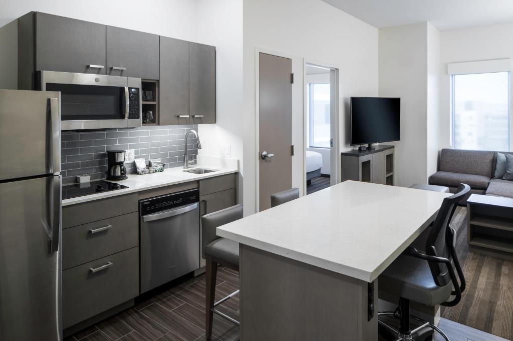 a kitchen with stainless steel appliances and a living room at Hyatt House Tempe Phoenix University in Tempe