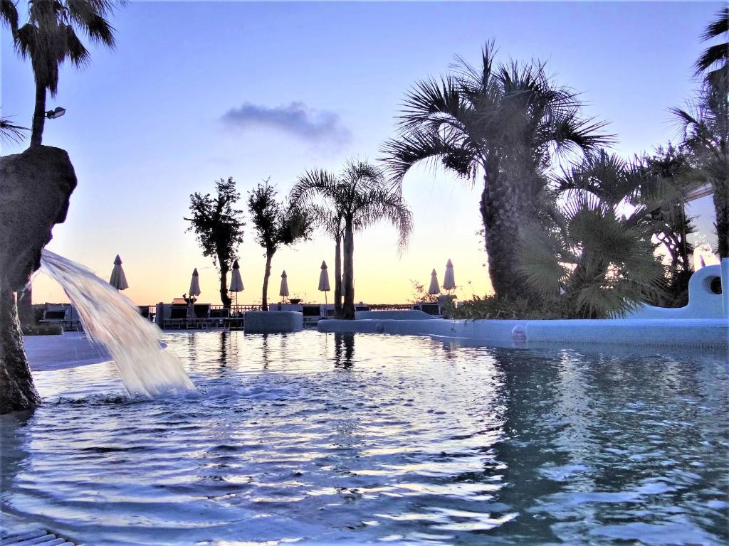 una fuente en medio de una piscina con palmeras en Hotel Myage, en Isquia