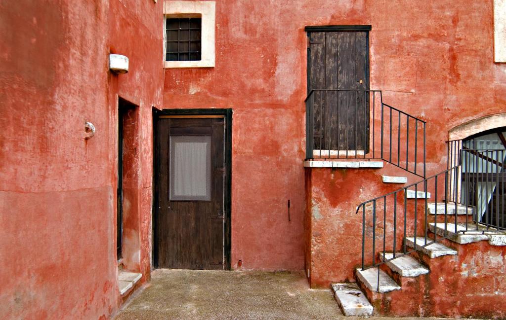 a red building with a door and a staircase at Masseria Spina Resort in Monopoli