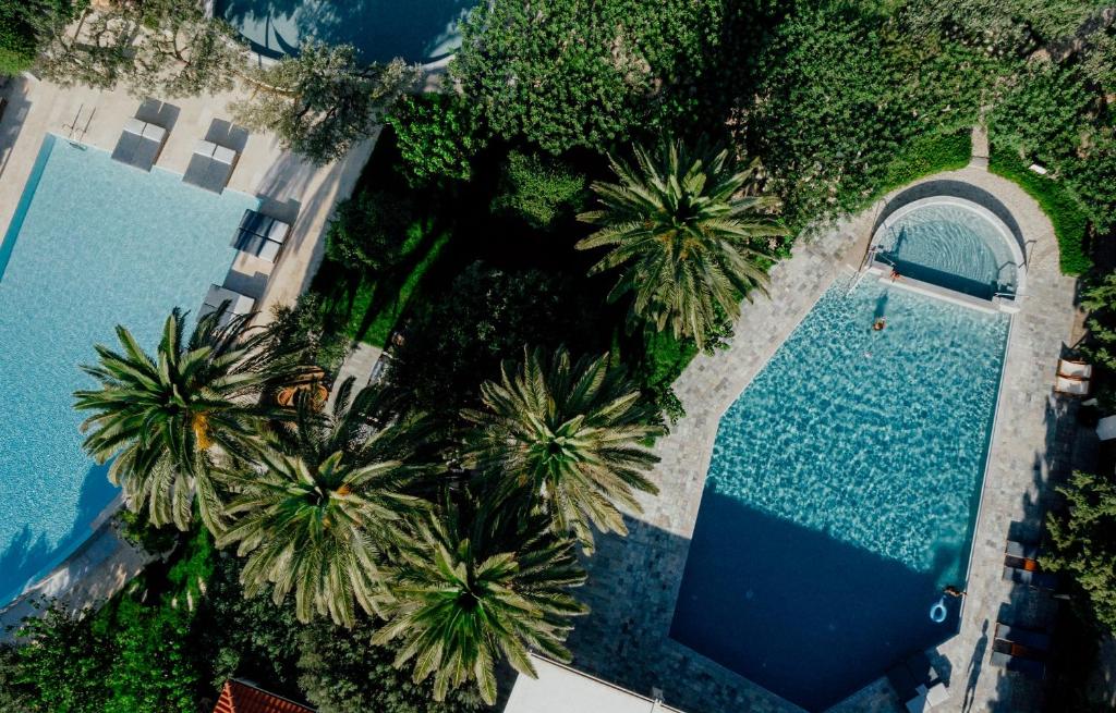 uitzicht over twee zwembaden met palmbomen bij Paralos Irini Mare in Agia Galini
