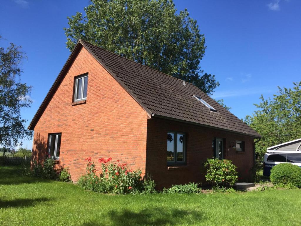 una casa de ladrillo rojo con techo negro en Ferienhaus mit Garten in Nordseenähe, en Langenhorn