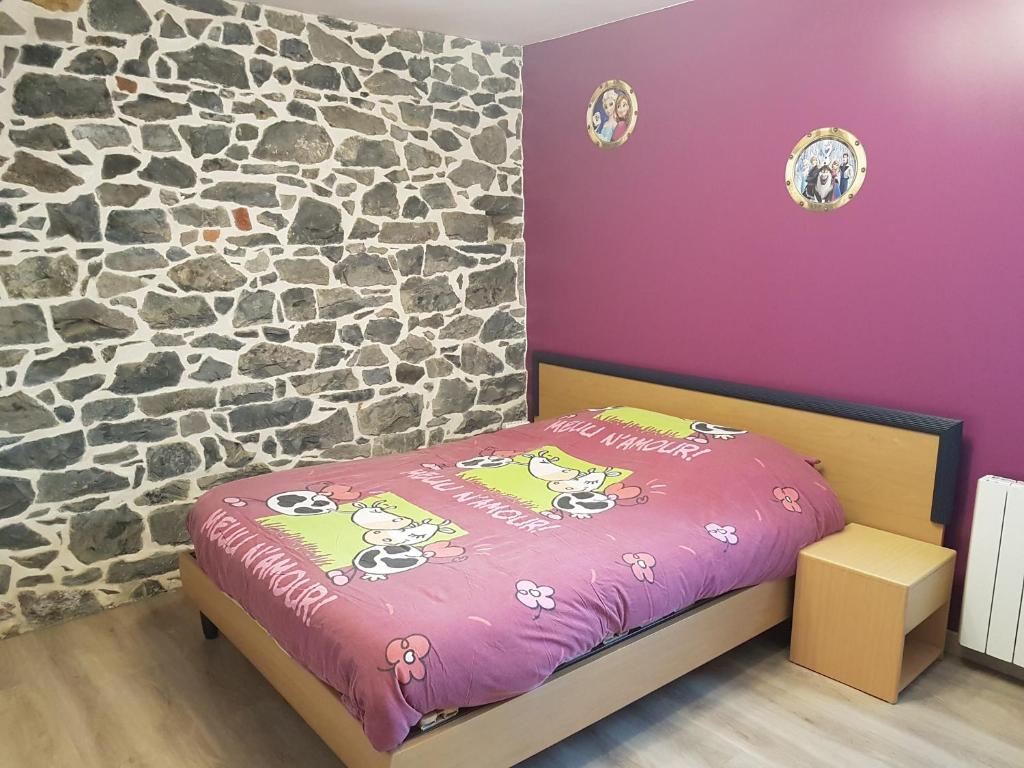 a bedroom with a bed with a stone wall at Chambre Rose à la Campagne 