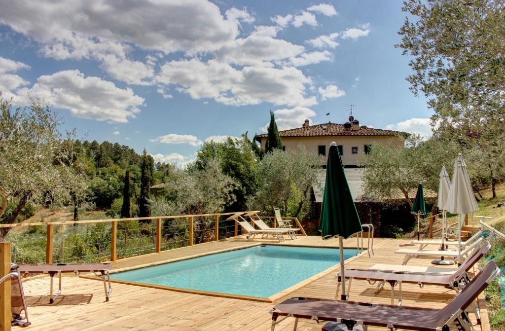 a pool on a wooden deck with chairs and a house at Il Fienile in Figline Valdarno