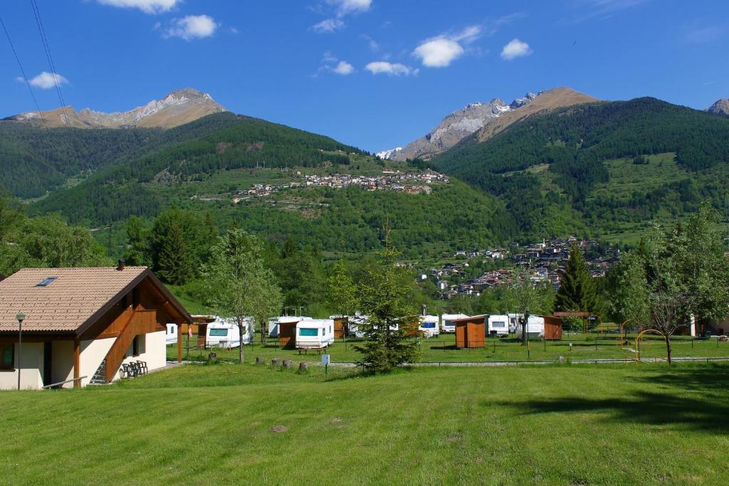 a field with a house and mountains in the background at Chalet Presanella in Temù