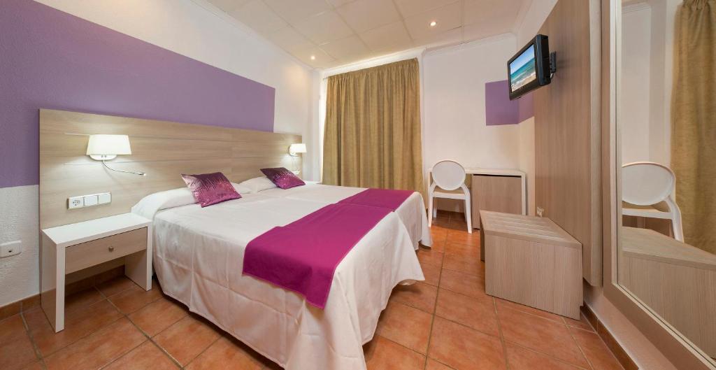 een hotelkamer met een bed en een flatscreen-tv bij Hostal Adelino in San Antonio